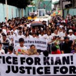 Mourners display a streamer during a funeral march for Kian delos Santos, a 17-year-old student who was shot during anti-drug operations in Caloocan
