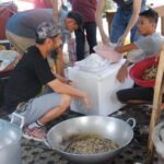 Nagkukuwentuhan ang mga boluntaryo ng SAKA at mga welgista habang nagpiprito ng tawilis